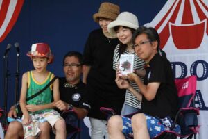 三条防災ステーションで開かれている「水曜どうでしょうキャラバン」でファンと記念写真を撮る藤村忠寿さんと嬉野雅道さんの2人のディレクター