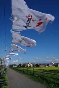 電鉄の路線跡地の遊歩道の上を小学生などがメッセージを書いたTシャツ300枚が泳ぐ