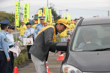 三条市大島の国道8号車両駐車帯でドライバーに交通安全啓発グッズを手渡す国定市長