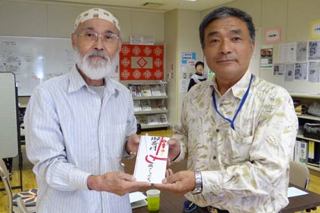 「ひばり」の代表、佐竹さん(左)に2万円を手渡す大崎コミュニティ「どんぐりころころ大崎」の高橋副会長