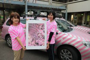 燕三条 工場の祭典のシンボル、ピンクのストライプで飾った三条市の広報車とストライプのTシャツを着た職員