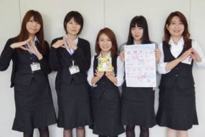 「なんかん育ち」のイメージソング『なんかん育ちのテーマ』を披露するJAにいがた南蒲の職員がおむすびのポーズで、中央が作詞と歌を担当した吉田睦さん