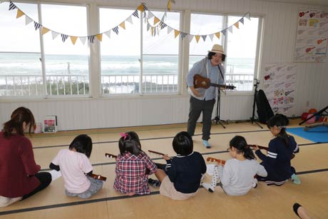 日本海を背にウクレレを指導するカツマーレーさん