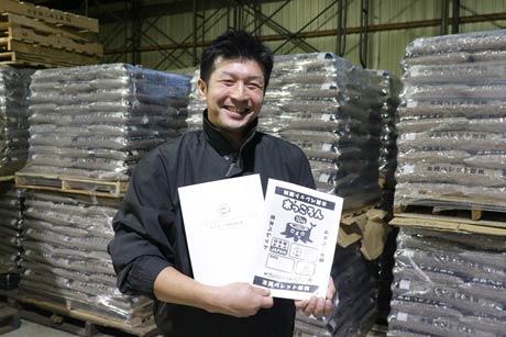 木質ペレット「木っころん」のエコマーク認定証と「木っころん」の新しいパッケージデザインを手に新潟エコエネルギーの相場社長