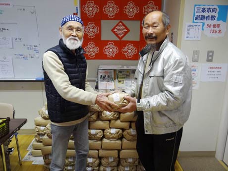 交流ルーム「ひばり」の佐竹代表(左)に米袋を手渡す江口さん