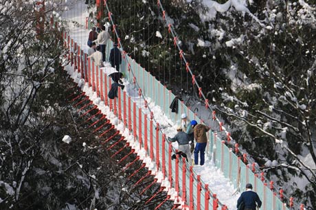 橋の上に積もった雪をシャベルで谷底に落とす