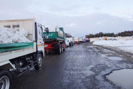 雪捨て場で行列をつくる雪を積んだダンプカーやトラック