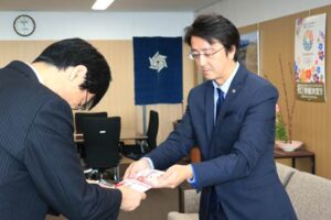父の遺志を継いで燕市の社会福祉に役立ててほしいと鈴木市長に100万円を手渡す山田さん(右)