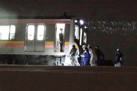  人身事故のあった列車の先頭部分を調べる警察官など
