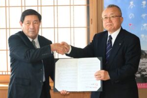 協定書に調印して握手する弥彦村建設業協同組合の菅原代表理事(左)と小林村長