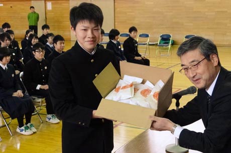 第四中での難関突破米の贈呈式、応援団長の3年生五十嵐諒真さんに(15)にJAにいがた南蒲の五十嵐大光営農経済担当常務理事から難関突破米を手渡す