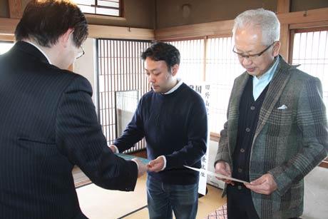 左から長谷川生涯学習課長、燕三条スタイルの小山代表社員、アックス都市開発の栗山代表取締役、国登録有形文化財の登録証と登録プレートを手渡す