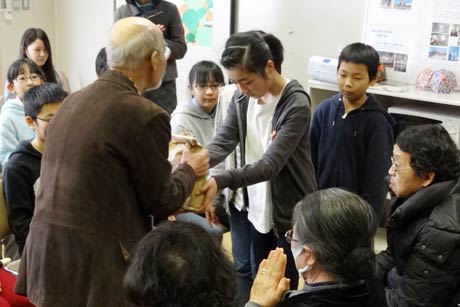 自分たちで育てたコメを避難者に手渡す保内小5年生
