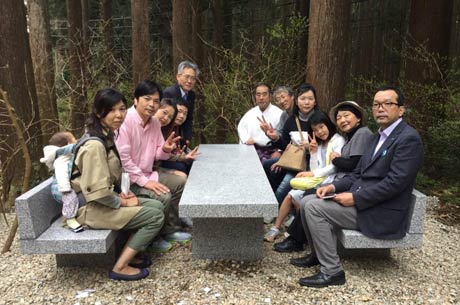 弥彦登山口に設置したベンチとテーブルに座って記念撮影する鳥部勝敏さんの遺族