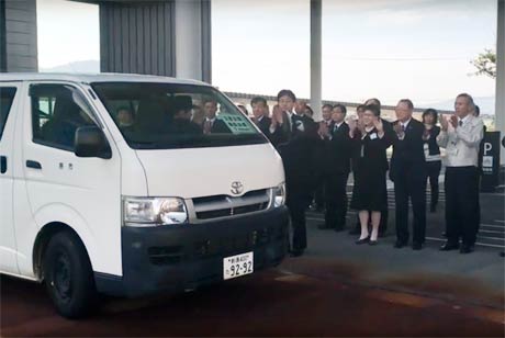  拍手で派遣職員2人が乗るバンを見送る
