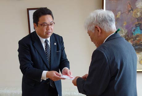 餞心亭おゝ乃の大野社長(左)が吉田副市長に10万円を手渡す