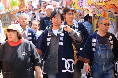 編んだ鈴緒とぴかぴかに磨いた鈴を露店が立ち並ぶ参道を抜けて八幡宮へ運ぶ