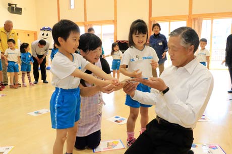 取ったかるたを同じチームの高齢者交通指導員にプレゼントする園児