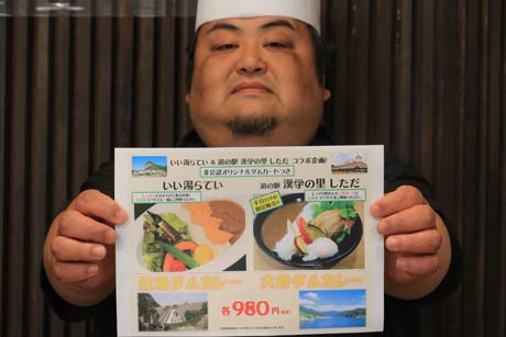 2施設で提供するダムカレーのちらしを手に「いい湯らてい」の渡辺孝秀統括料理長