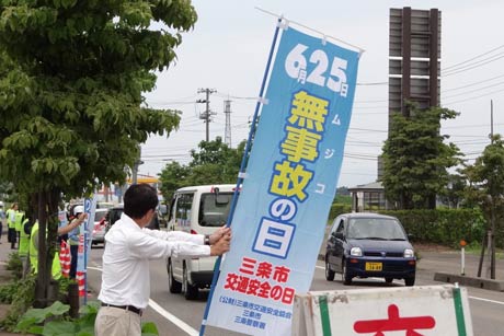 「無事故の日」ののぼり旗を掲げて交通安全を呼びかける
