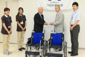 家具のまるやまの丸山義昭社長（中央左）からつばめ福祉会の吉田賢一理事長（中央右）に車いす2台の目録を手渡す