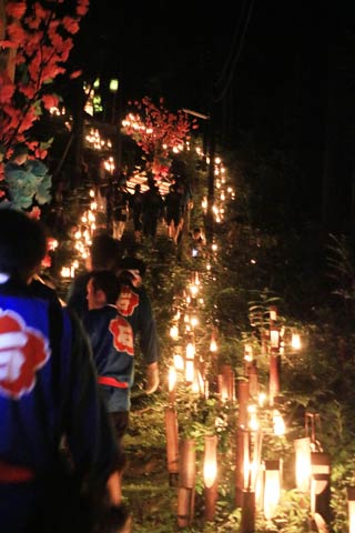 燈籠やろうそくがともる石動神社へ続く坂を二基の花燈籠を担いで登る