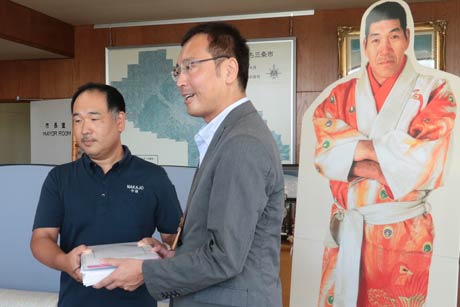 ジャイアント馬場の写真パネルを背に中條会長と国定市長