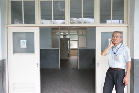 高い窓がユニークなデザインのトイレの前で同窓会の石崎順一会長