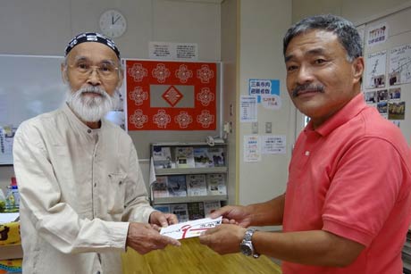  交流ルーム「ひばり」代表の佐竹紀さん(左)に寄付を手渡す大崎コミュニティ「どんぐりころころ大崎」の高橋茂会長