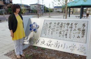 条南小学校跡地の校歌碑の前で話す「校歌を保存する会」の濱田会長