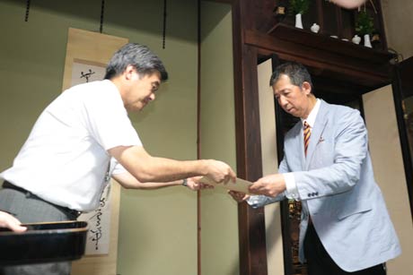 三条市生涯学習の金子課長(左)から「つるがや」の七代目柄沢さんに登録証を手渡す