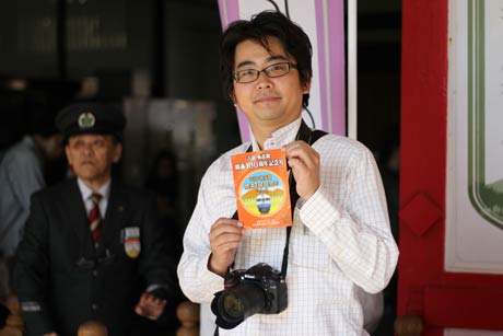 車内で配布された記念ステッカーを手に藤井芳輔さん
