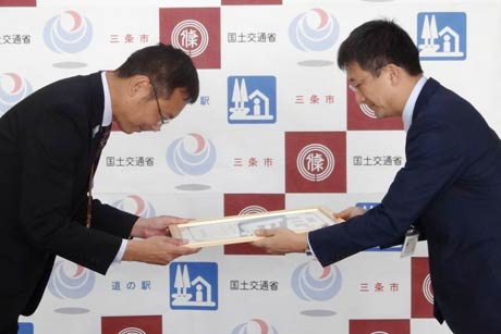 大江新潟国道事務所長(右)から国定市長に道の駅の登録証を手渡す