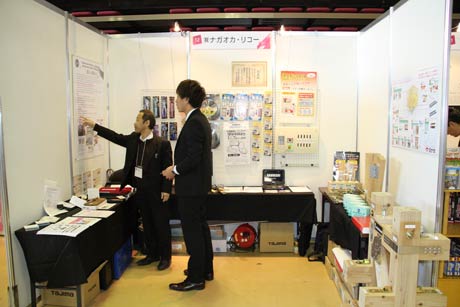 【株式会社ナガオカ・リコー】商品に表示する2次元（2Dシンボル）をPR。GS1QRと呼ぶQRコードにより、スマホなどで読み込むだけで取り扱い説明書や商品情報を表示でき、リコール情報などもプッシュ送信できる。多言語対応なのも特徴。