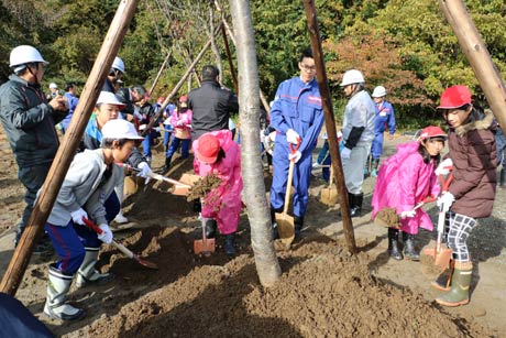 旧国上小学校跡地で行われたサクラ移植式でシャベルで土を盛る分水北小4年生