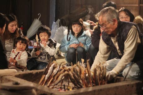 旧武石家住宅での「むかしばなしと昔の遊び」でいろりで焼いたイワナを味わう