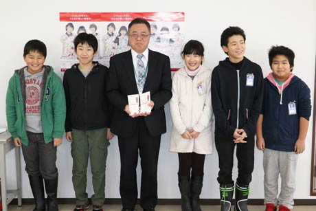 赤い羽根の校内募金に寄せられた善意と学校田で収穫したコメを販売して得た1万5千円を寄付を燕市社会福祉協議会に届けた粟生津小児童と燕市社協の本間事務局長