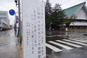 スタート地点となる三条市総合福祉会館前に設置された三条市元旦マラソン大会に対する協力を求める看板