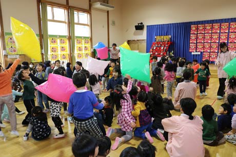 空気を入れたビニール袋で夢中で遊ぶ園児