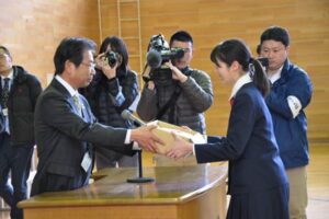 三条市立第四中学校の贈呈式で3年生代表の長谷川あずささんに「難関突破米」を手渡すJAにいがた南蒲の佐野行雄代表理事理事長