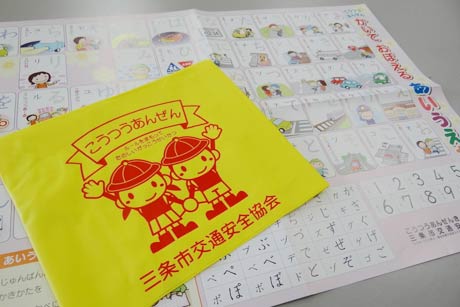  三条市交通安全協会が三条市教育委員会に寄付した新1年生用のランドセルカバーと交通安全あいうえお表