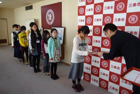 子ども記者一人ひとりに国定市長から図書カードを手渡す