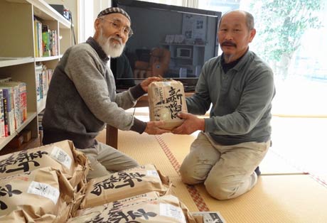 「ひばり」の佐竹紀代表に栽培したコシヒカリを手渡す渡辺幸蔵さん