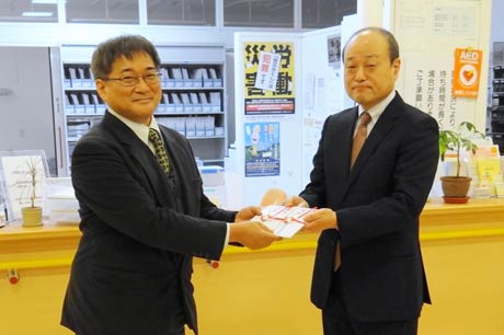 加茂市医師会の土田清会長(右)から県央医師会応急診療所長の水野春芳三条市医師会会長に加茂市民から寄付を手渡す