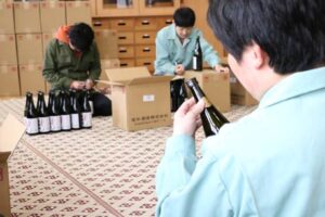 旧荒沢小学校で行われた芋焼酎「五輪峠」に封緘紙のシール張る作業