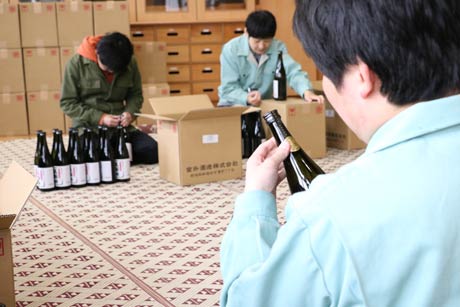  旧荒沢小学校で行われた芋焼酎「五輪峠」に封緘紙のシール張る作業