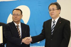 包括連携協定を締結して握手する新潟経営大学の渡辺学長(左)と加茂信用金庫の阿部理事長
