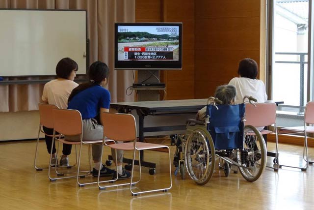 下田公民館でテレビで大雨のニュースを見る避難者