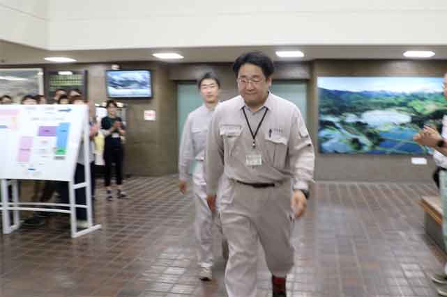  市役所玄関で数十人の職員の拍手に送られて出発する先遣隊の2人