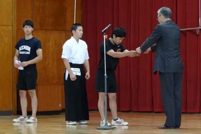  梨本同窓会長からインターハイ出場のウエイトリフティング、レスリング、弓道の3つの部活動に激励金を手渡す